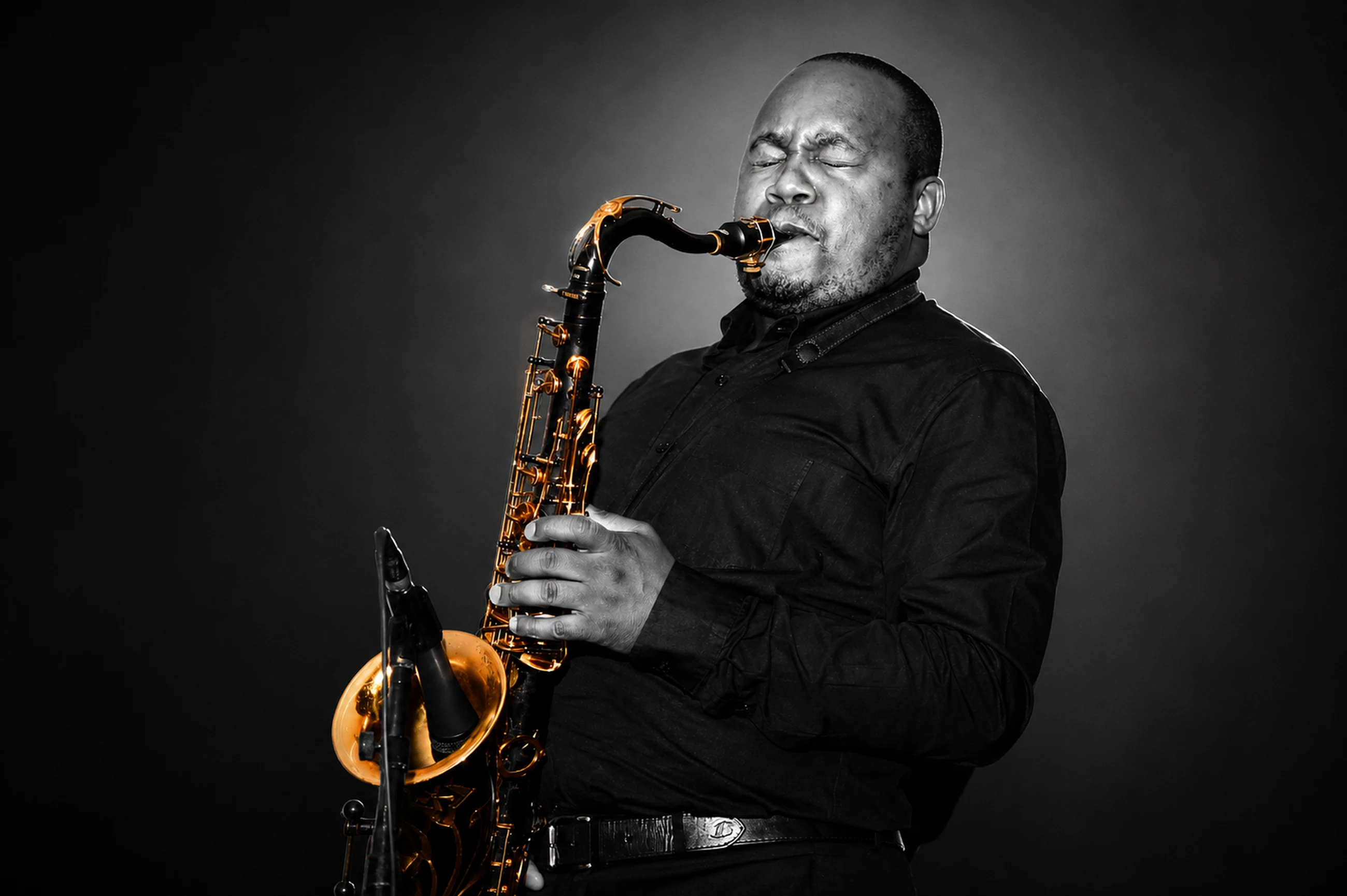 Edward Parseen in black, playing against a darkened studio backdrop